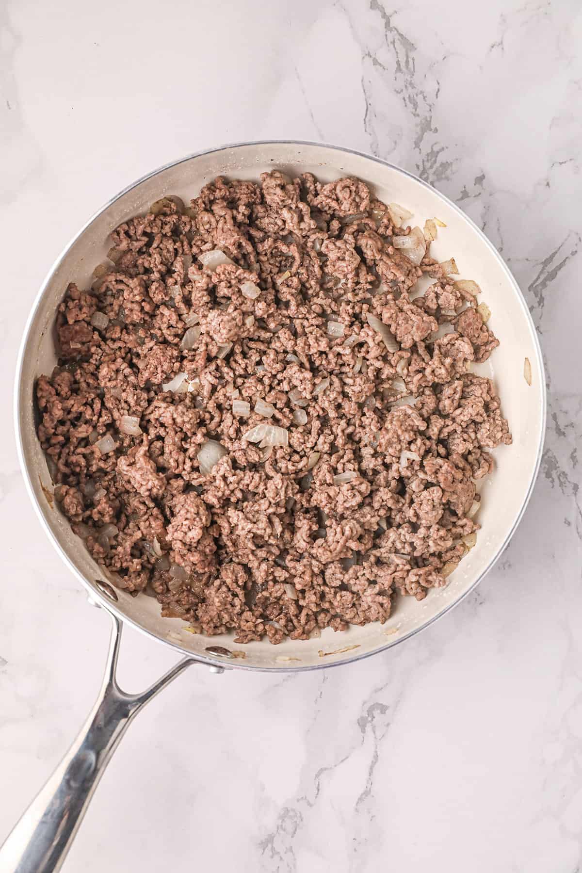 Beef and onions cooking in a skillet.