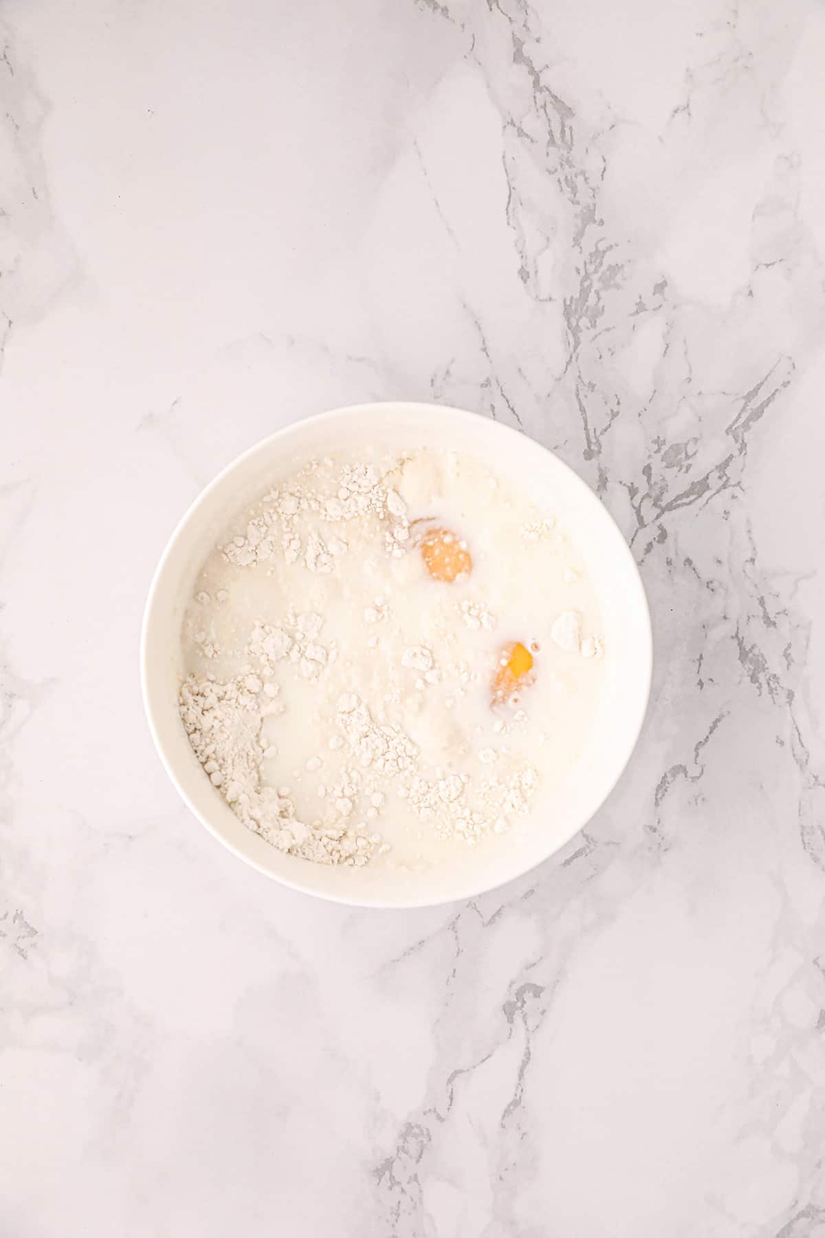 Eggs, milk, and baking mix in a white bowl.