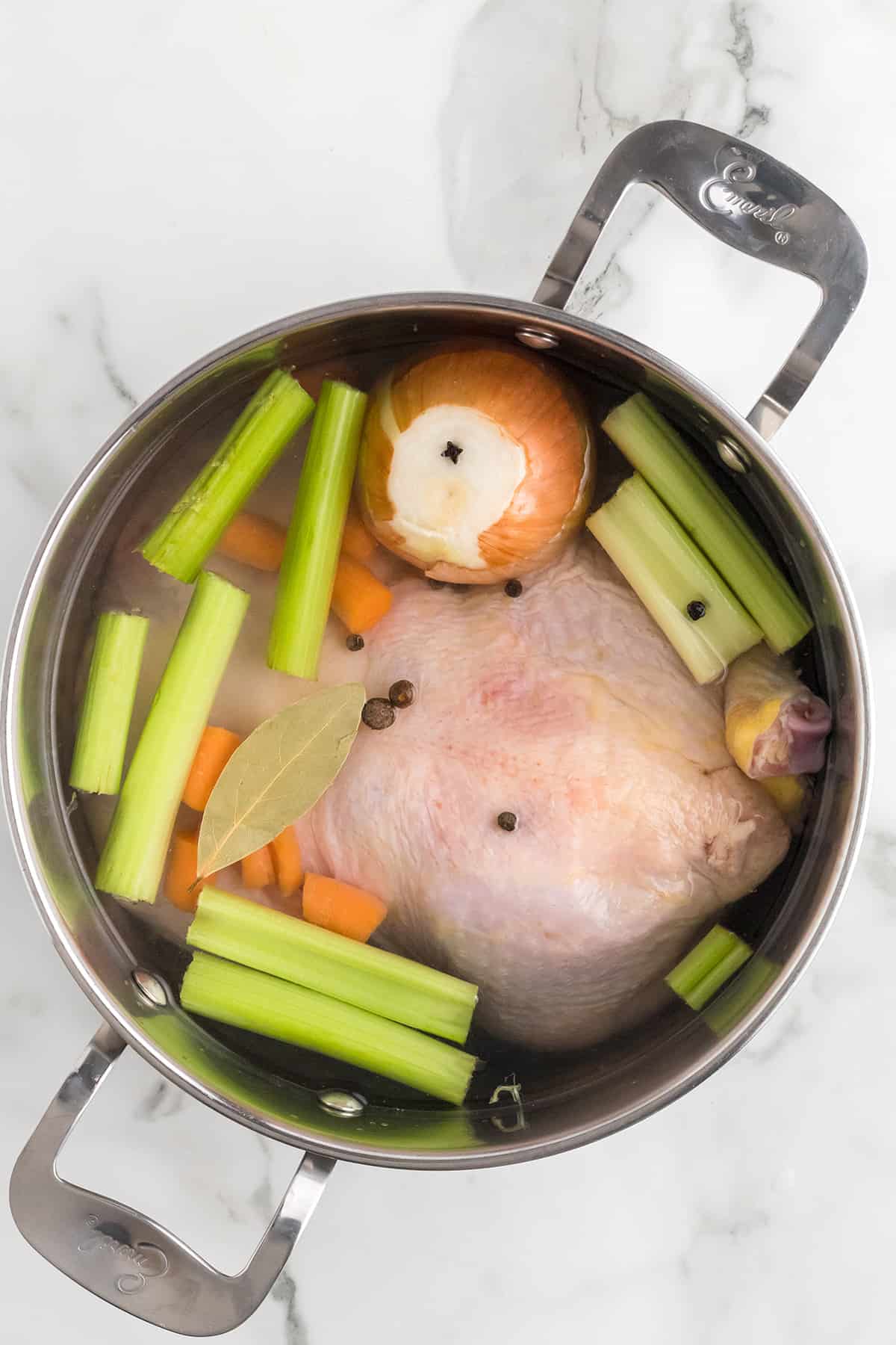 Chicken and aromatic vegetables in a pot with water.