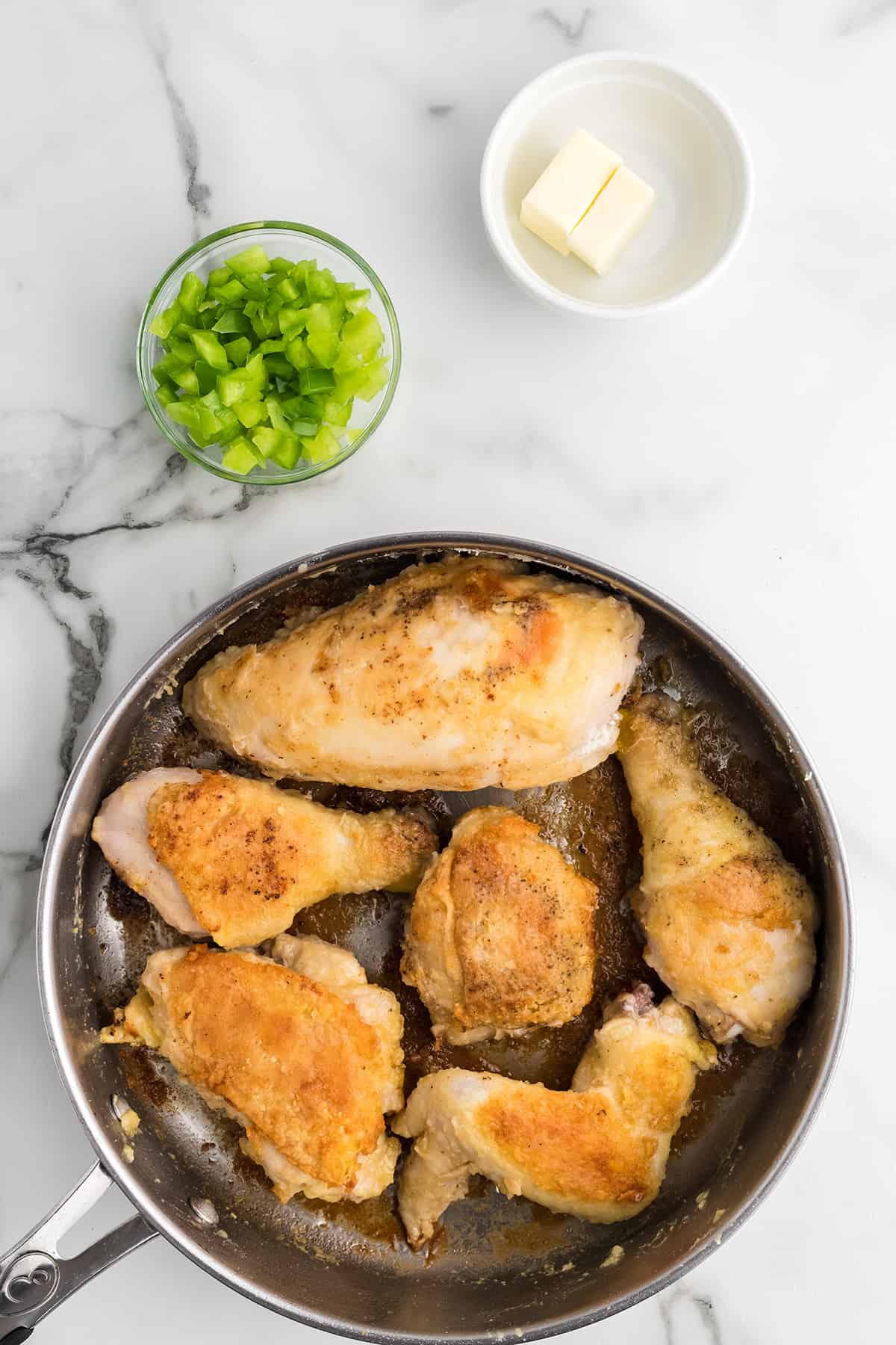 Browned chicken pieces in a skillet.