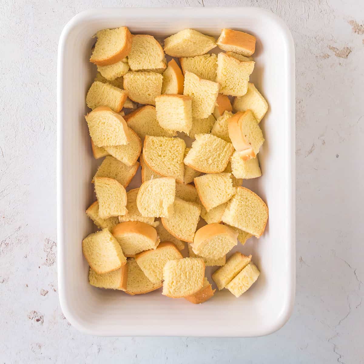 Cubed brioche in a buttered baking dish.