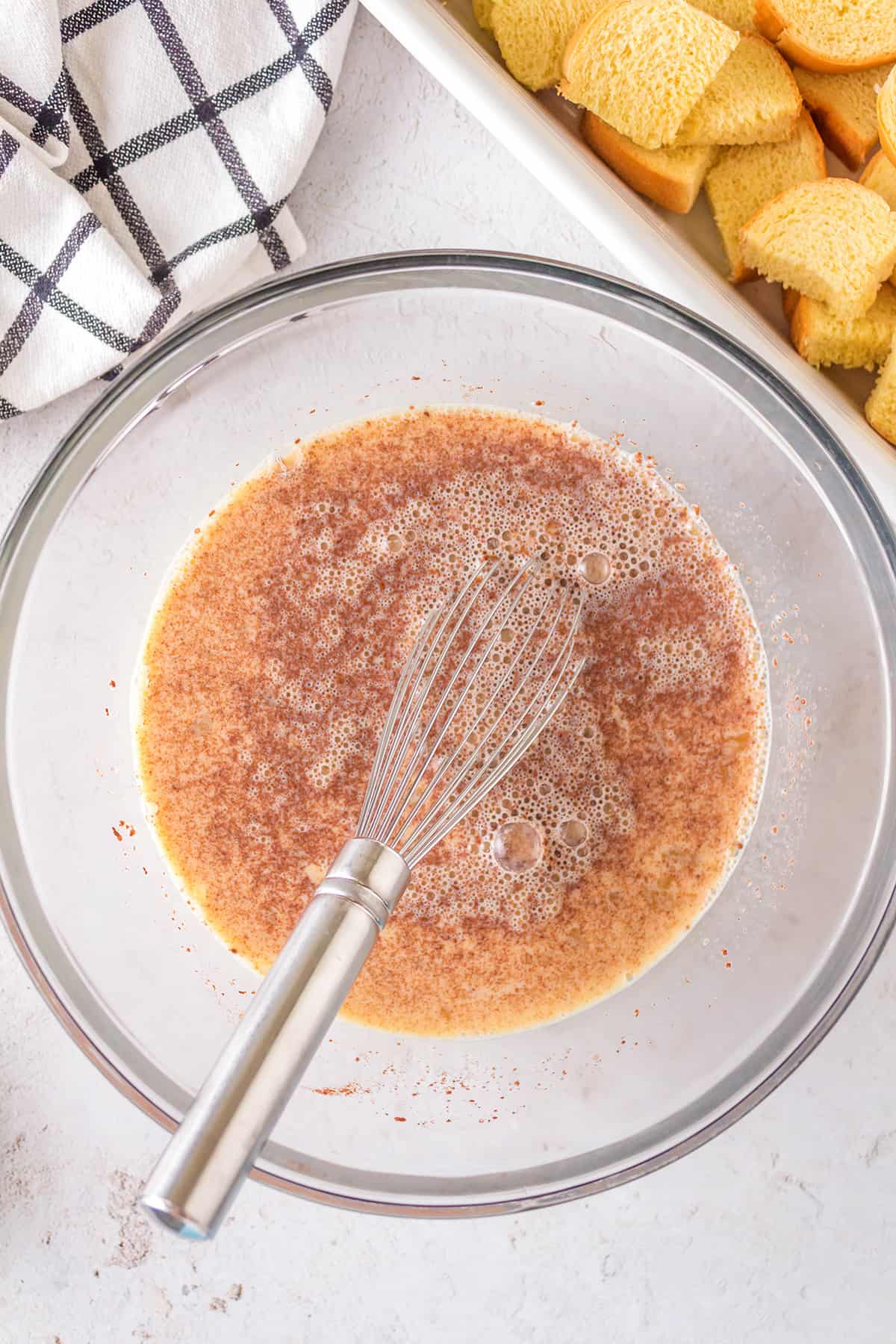 Egg and milk mixture with a whisk in a mixing bowl.