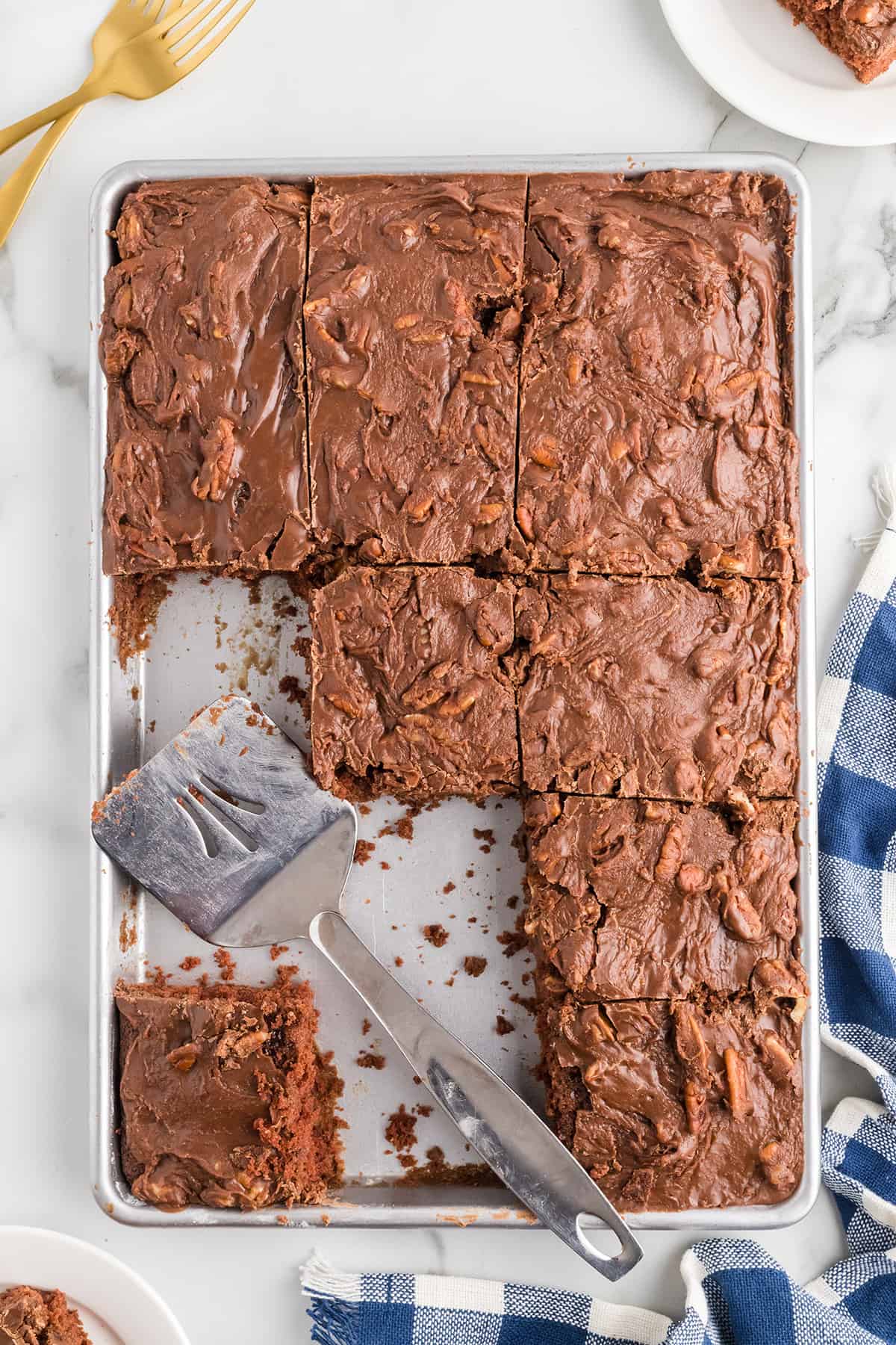 Cake squares cut on a baking sheet with a spatula to the side.