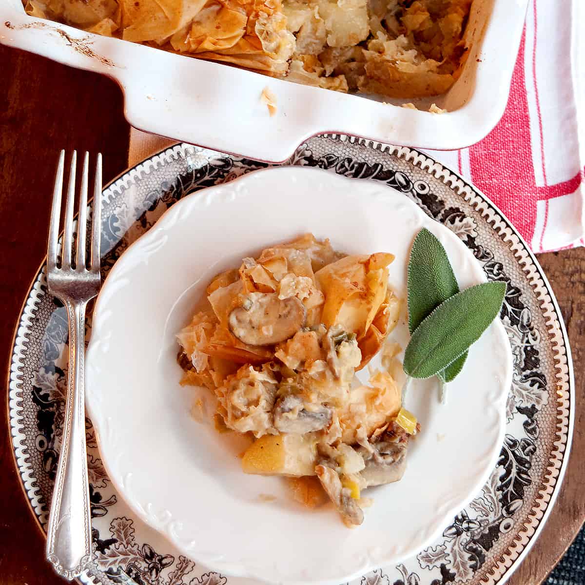 A serving of the finished pie on a white plate with fresh sage on the side.