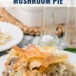 A serving of chicken, leek, and mushroom pie with flaky crust on a white plate, with salt and pepper shakers.