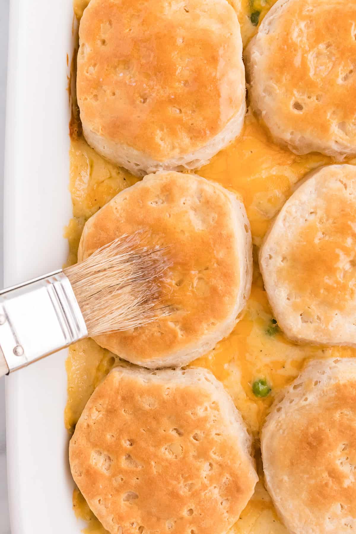 Brushing biscuits with melted butter.