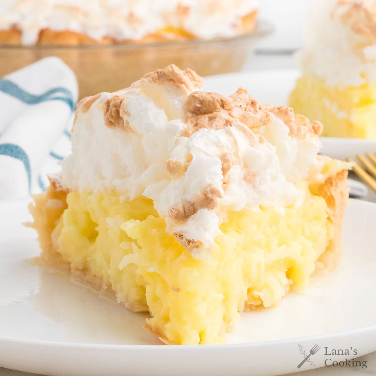 A slice of lemon meringue pie with a golden crust and fluffy, toasted meringue on top.