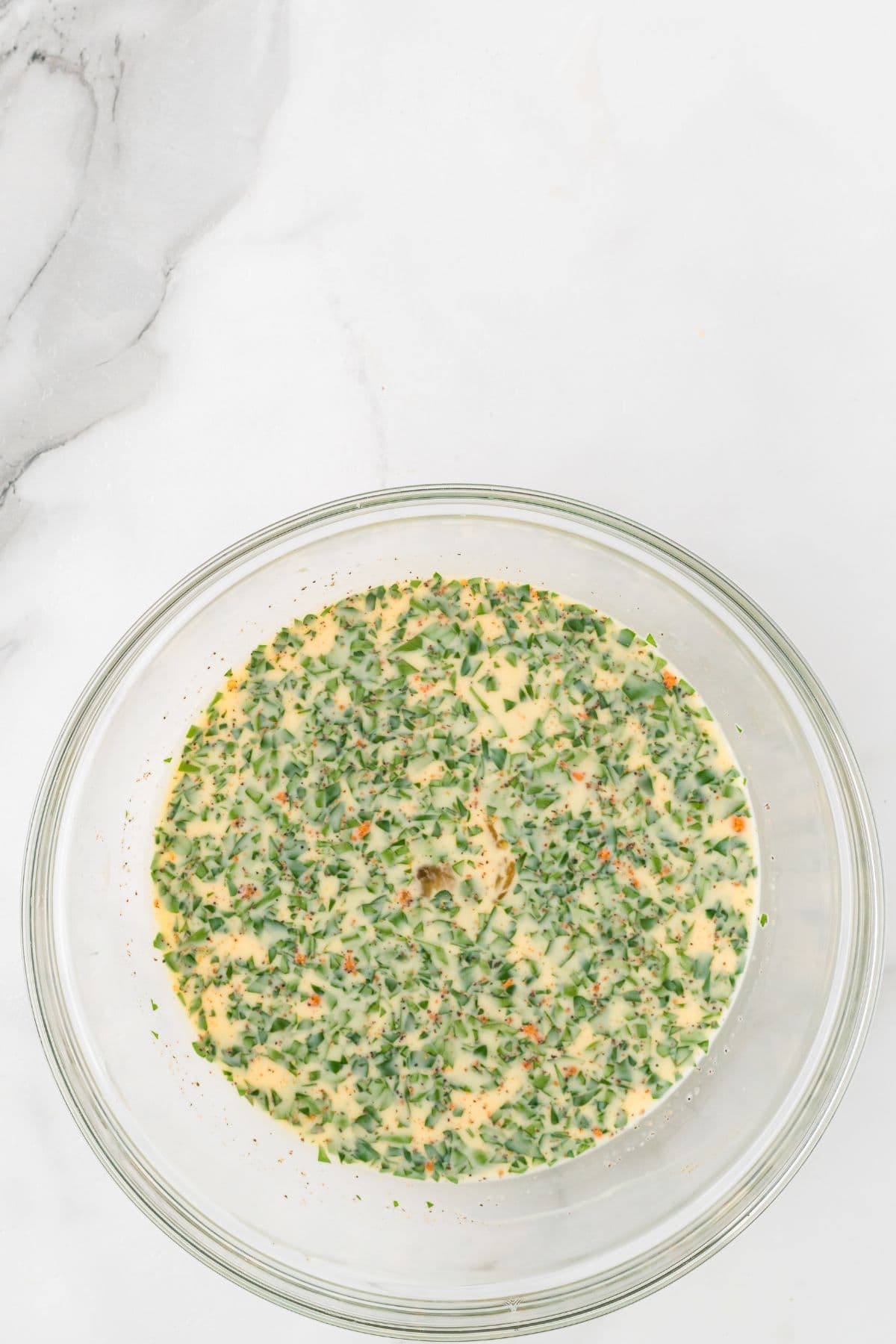 Eggs after the milk, parsley, and seasonings are added and whisked together.