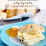 A scone with butter and jam on a decorative plate.