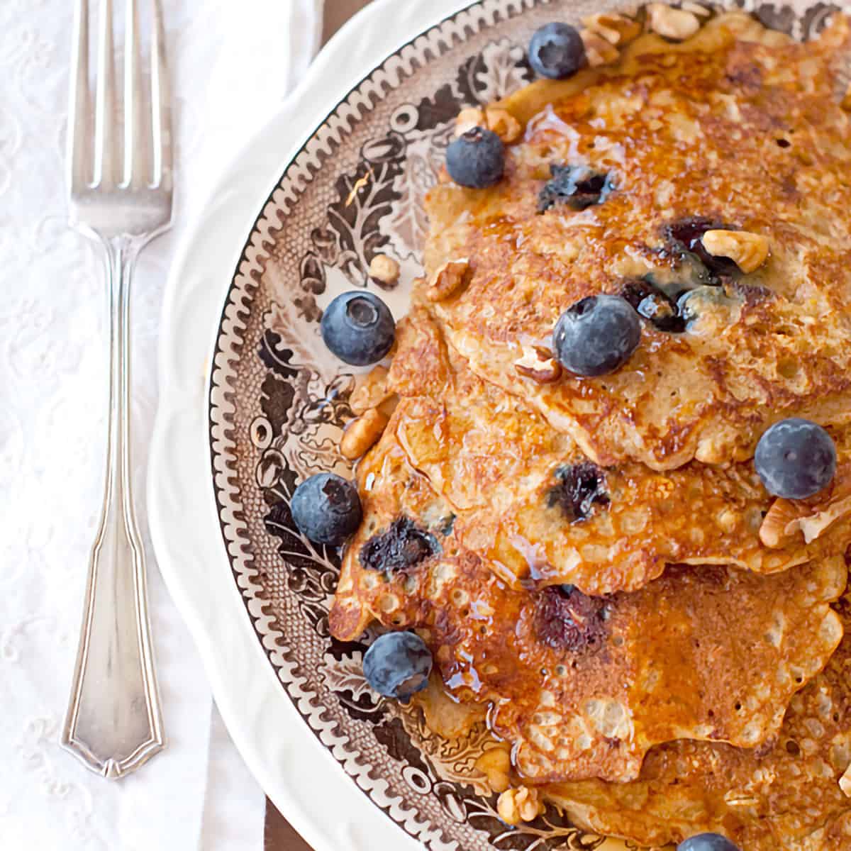 A stack of oatmeal blueberry pancakes on a decorative plate.