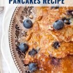 Oatmeal blueberry pancakes on a decorative plate with blueberries and syrup, recipe text above.