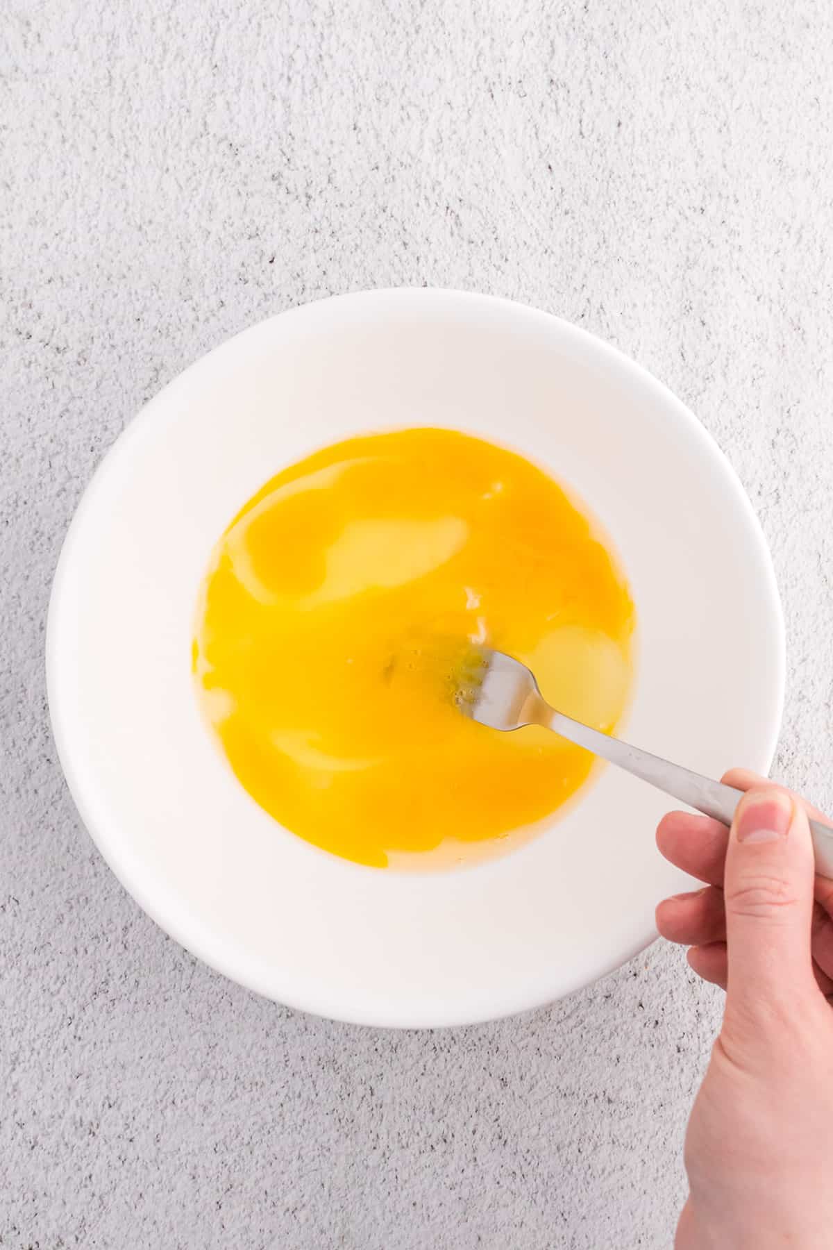 Beating eggs in a bowl.