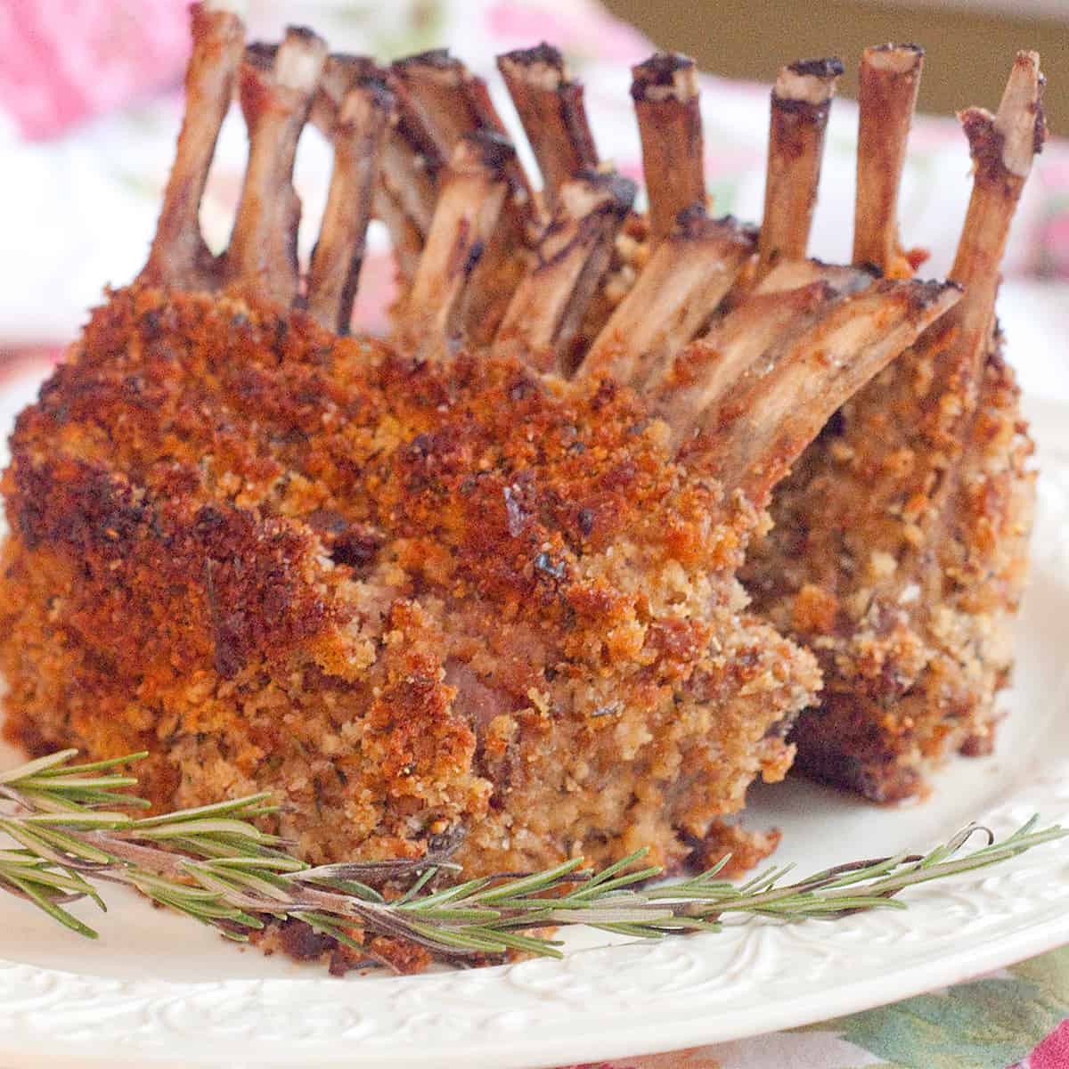 Finished rack of lamb on a white serving plate.