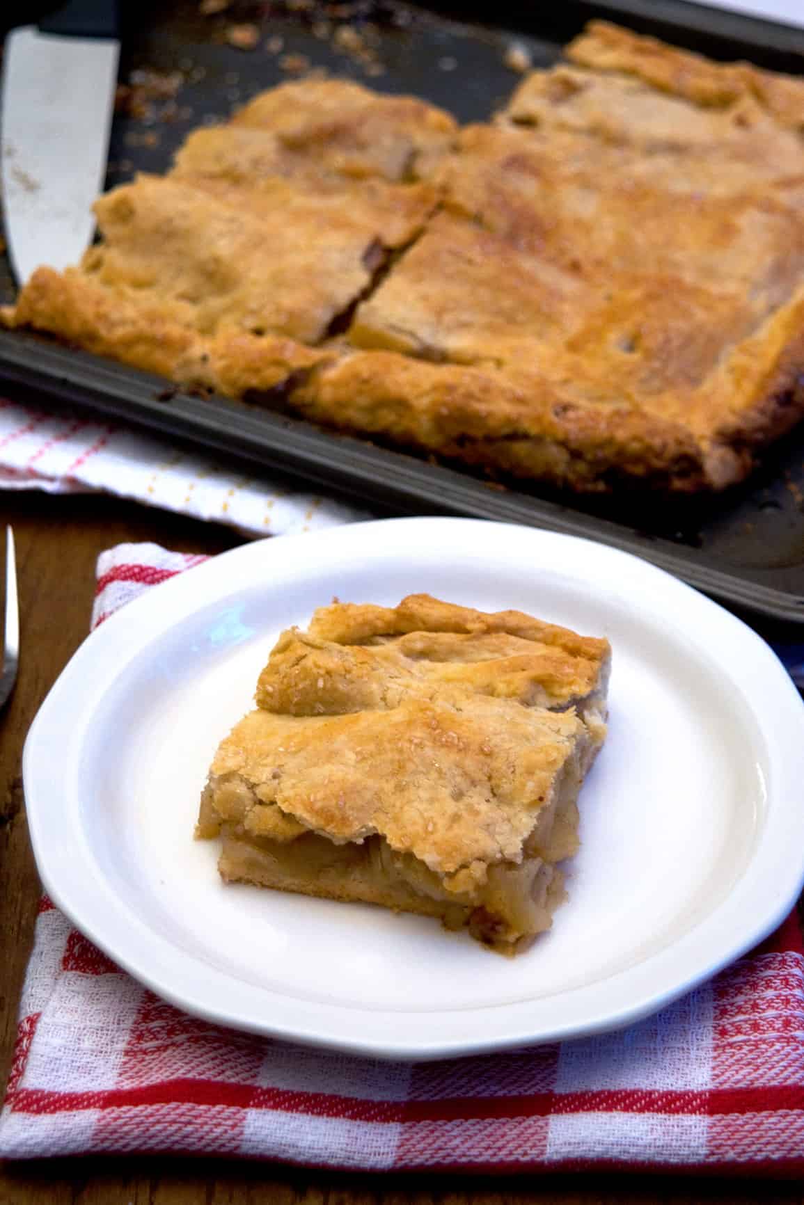 A slice of apple slab pie on a white plate.