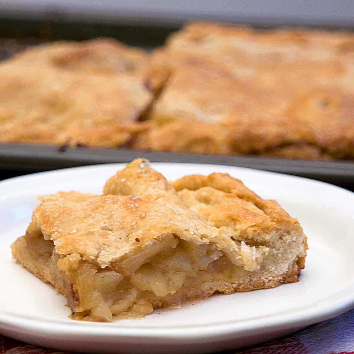 A slice of apple slab pie on a white plate.