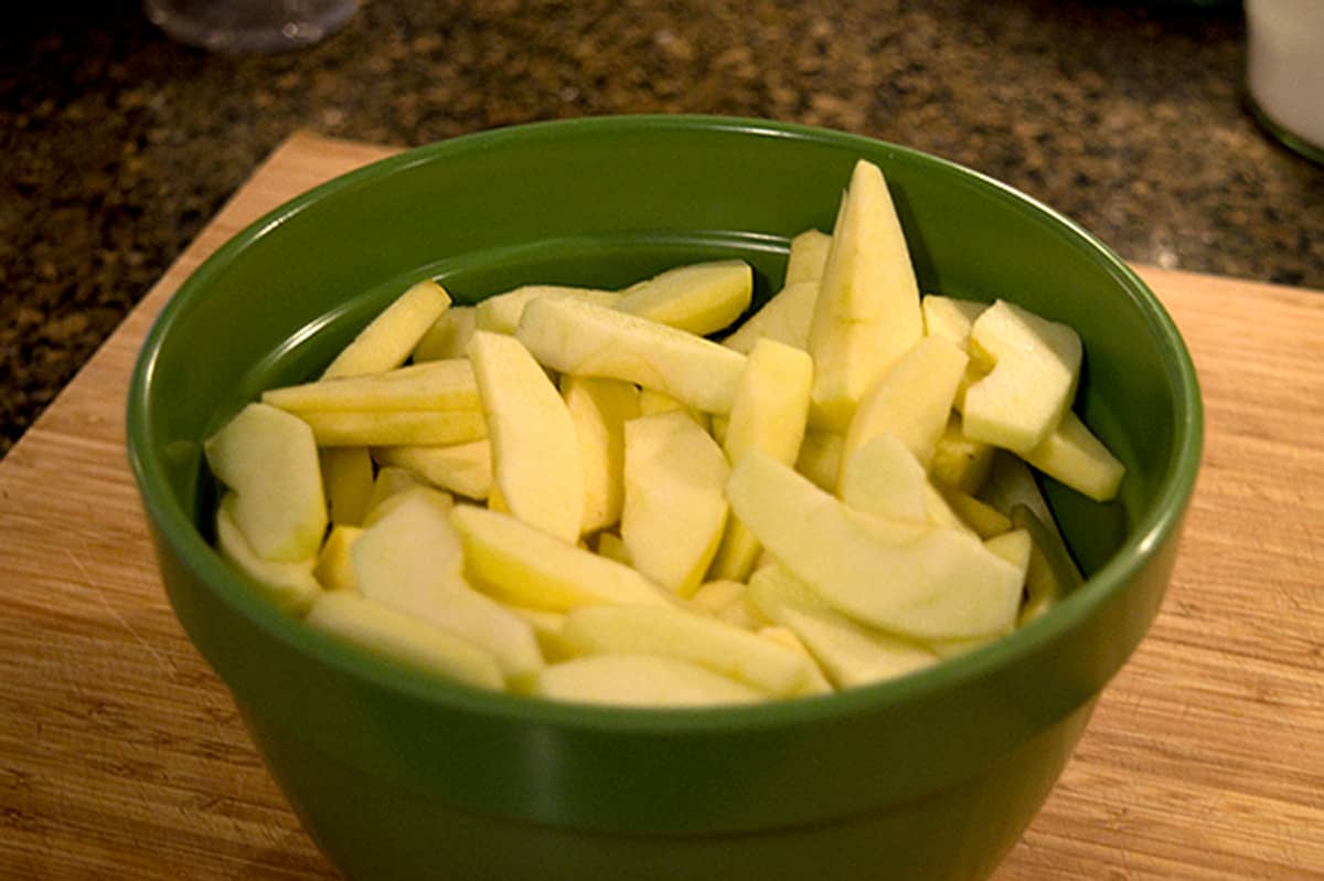 Apple slices in a large green bowl.