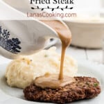 Gravy being poured onto country fried steak on a plate with mashed potatoes.