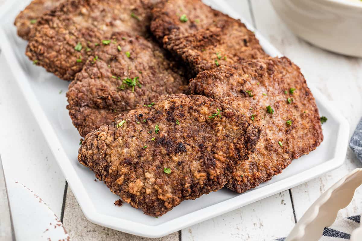 A platter filled with finished country fried steak.