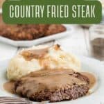 A plate with country fried steak topped with brown gravy, served alongside mashed potatoes with gravy. A fork rests on the plate. Another plate of steak and a pepper shaker are in the background. Text reads “Southern Country Fried Steak.”.