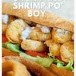 Close-up of an oven fried shrimp po boy sandwich with lettuce, tomato, and sauce on a hoagie roll.