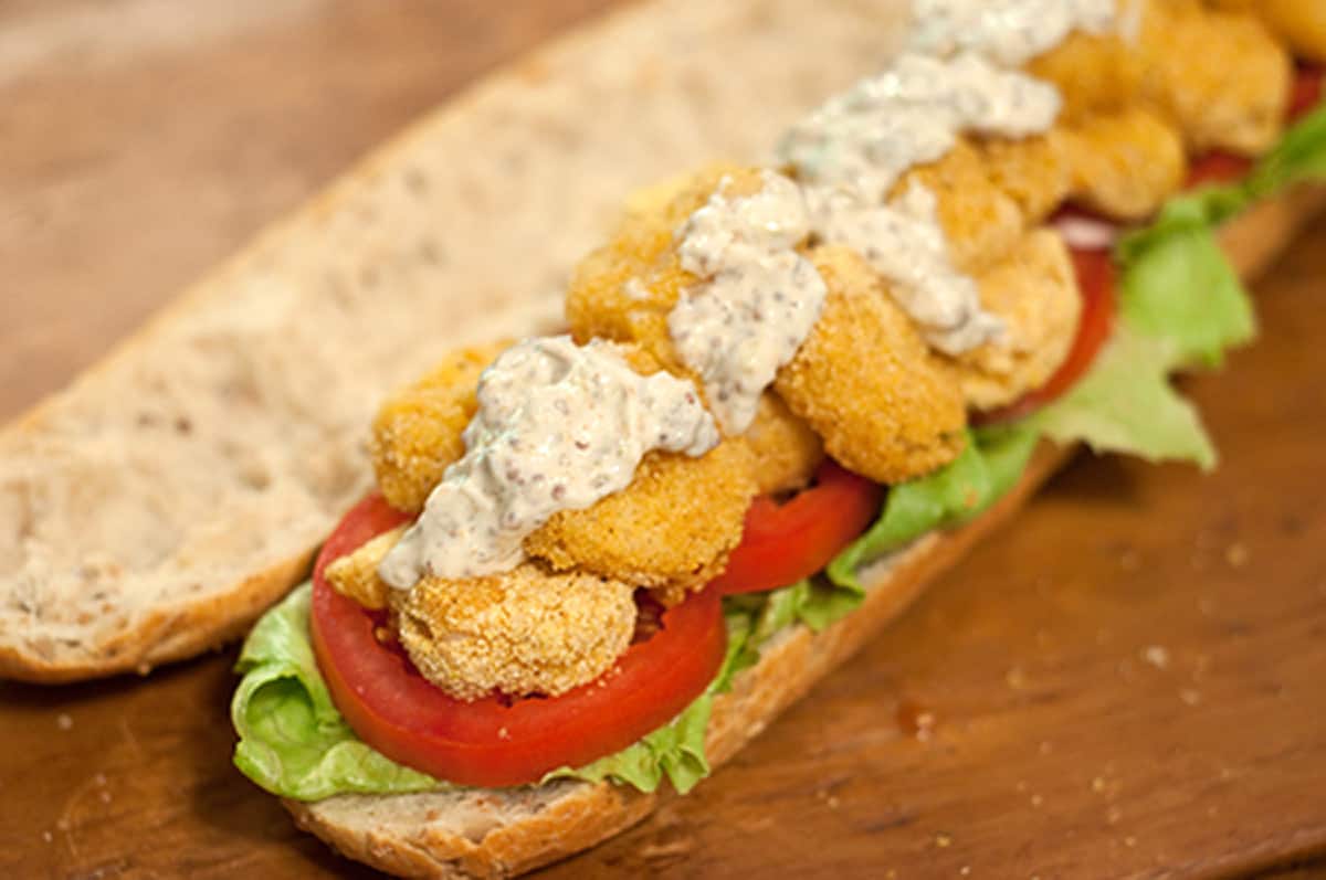 Assembling the sandwich with baguette, lettuce, tomato, and Remoulade sauce.