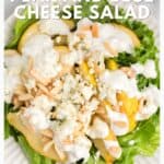 Pear and blue cheese salad on lettuce, topped with dressing and slivered almonds, on a white plate.
