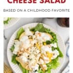 A plate of pear and blue cheese salad with lettuce, cheese, and dressing on a white table.