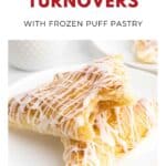 Two peach turnovers with icing drizzle on a white plate, made with golden, flaky puff pastry.
