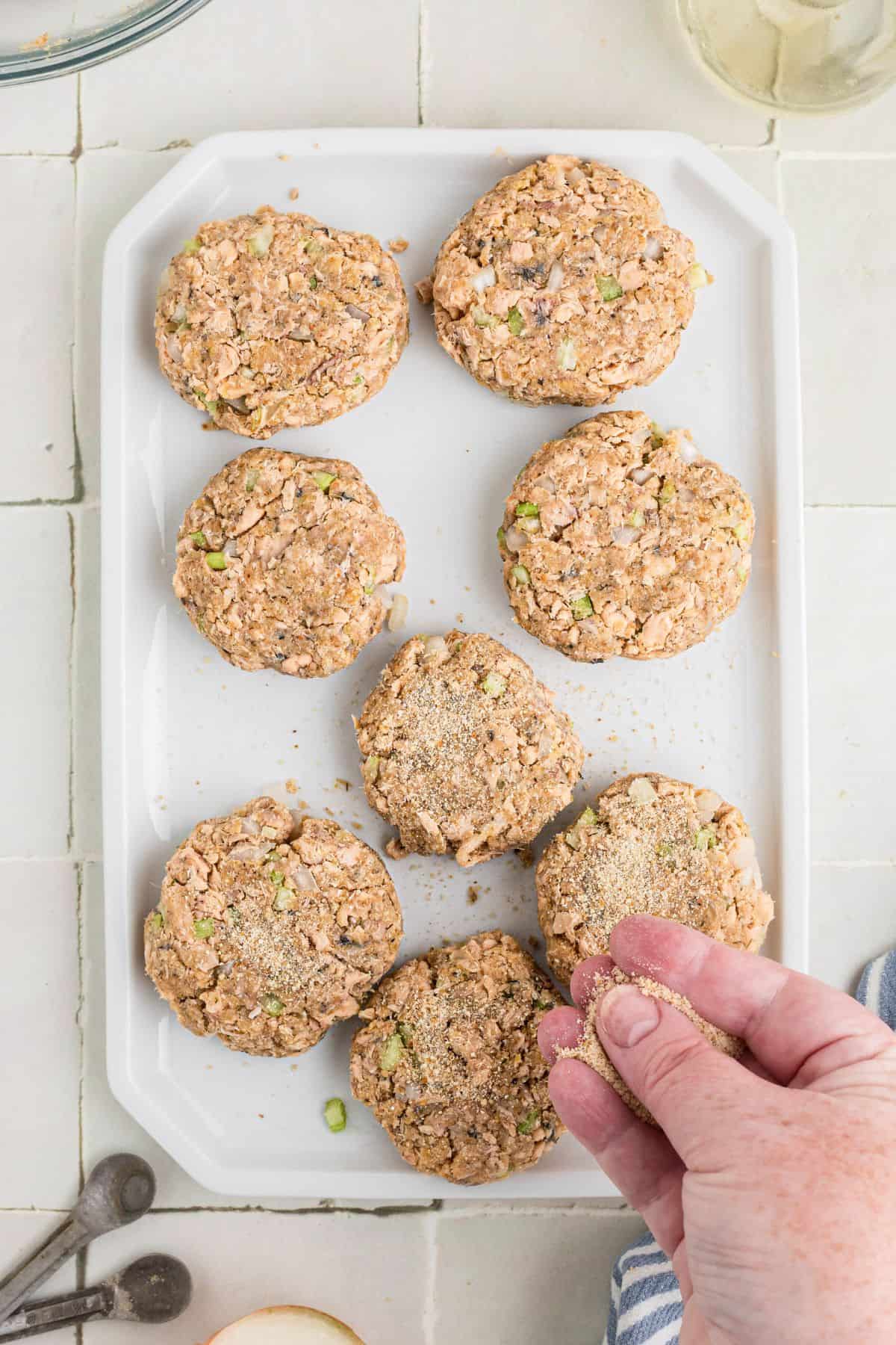 Bread crumbs being sprinkled on top of the formed croquettes.