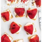 Overhead view of crackers topped with cream cheese and strawberries, arranged neatly on a white surface.