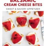 Overhead view of crackers topped with cream cheese and strawberries on a white surface.