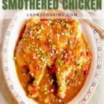 An oval dish with Creole-style smothered chicken topped with sauce and chopped green onions, placed on a light-colored cloth with a spoon beside the dish.