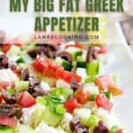 Close-up of a platter with feta dip topped with chopped tomatoes, cucumbers, olives, and green onions. Text overlay reads: Feta Dip, My Big Fat Greek Appetizer, lanascooking.com.