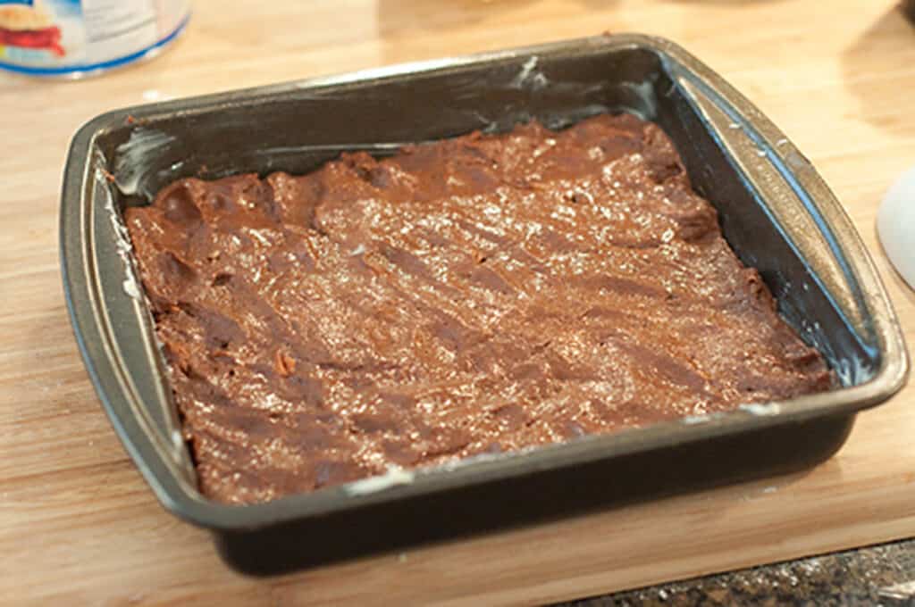 Brownie batter spread in a baking pan.