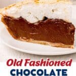 A slice of chocolate meringue pie with a thick chocolate filling and fluffy meringue topping on a white plate.
