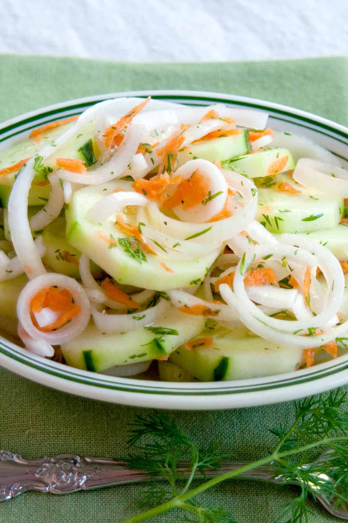 Sweet and sour cucumber salad in a bowl with a green napkin to the side.