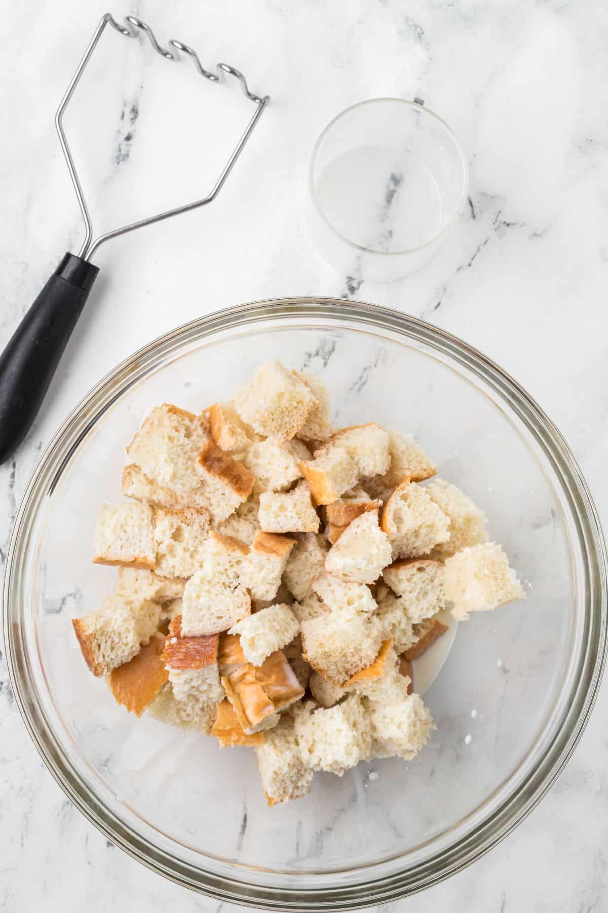 Bread cubes and milk in a mixing bowl.