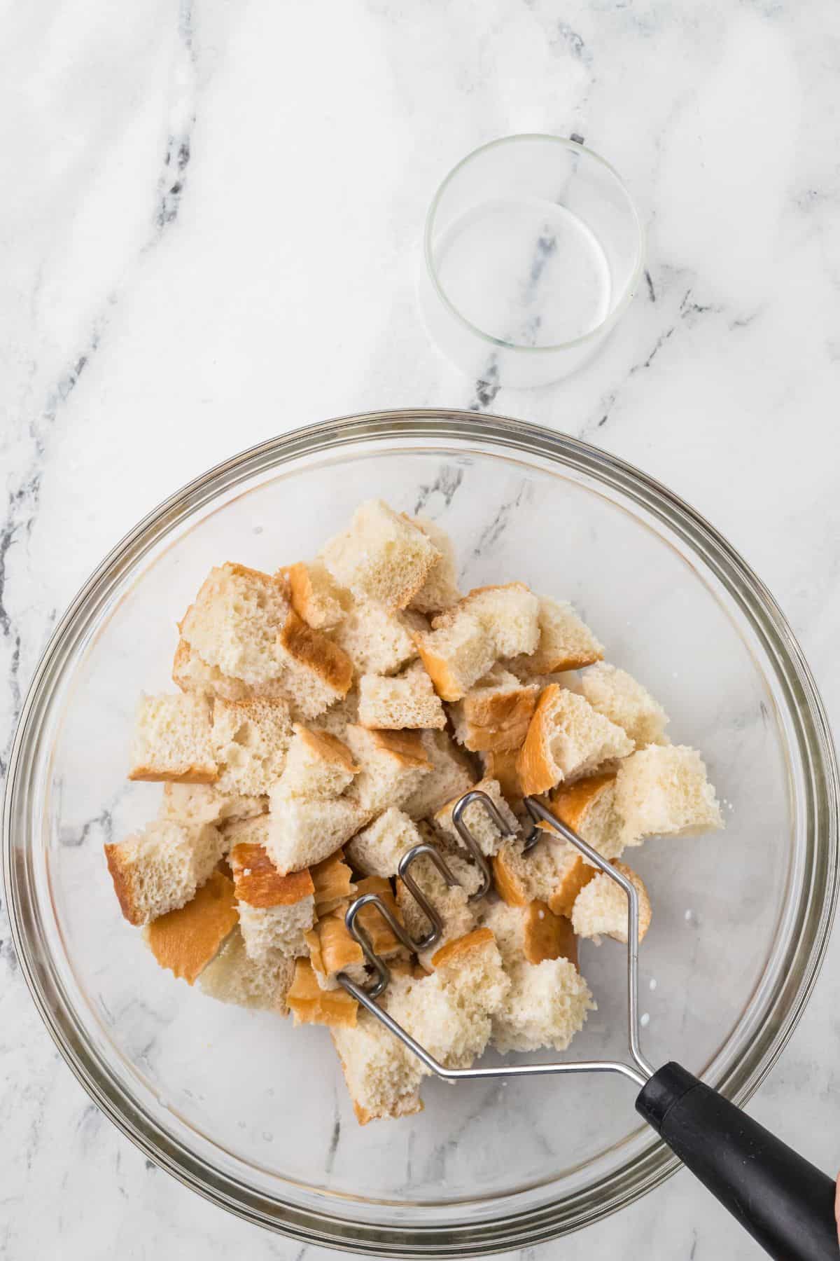 Bread cubes and milk being mixed in the bowl.