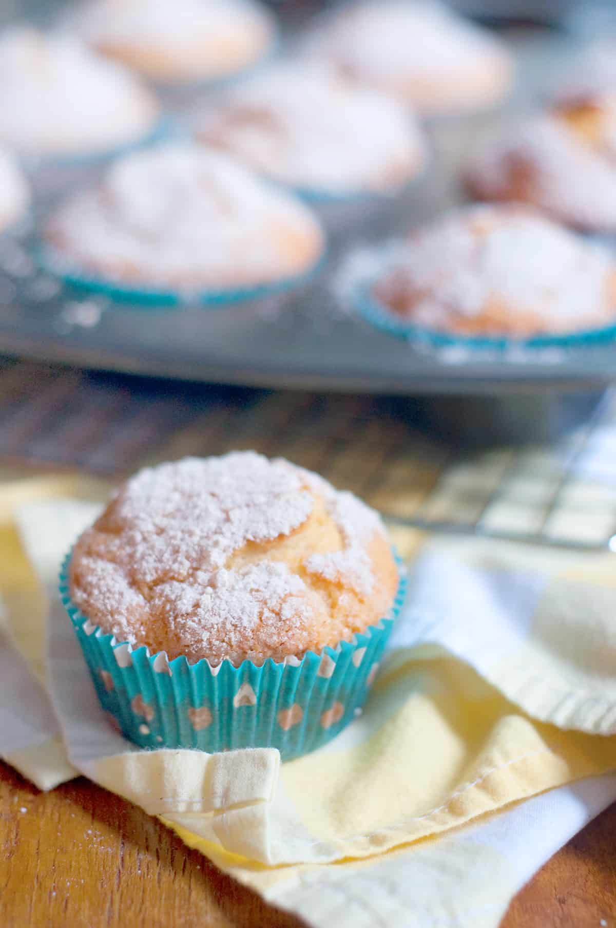 An orange blossom muffin sitting on a yellow and white napkin.