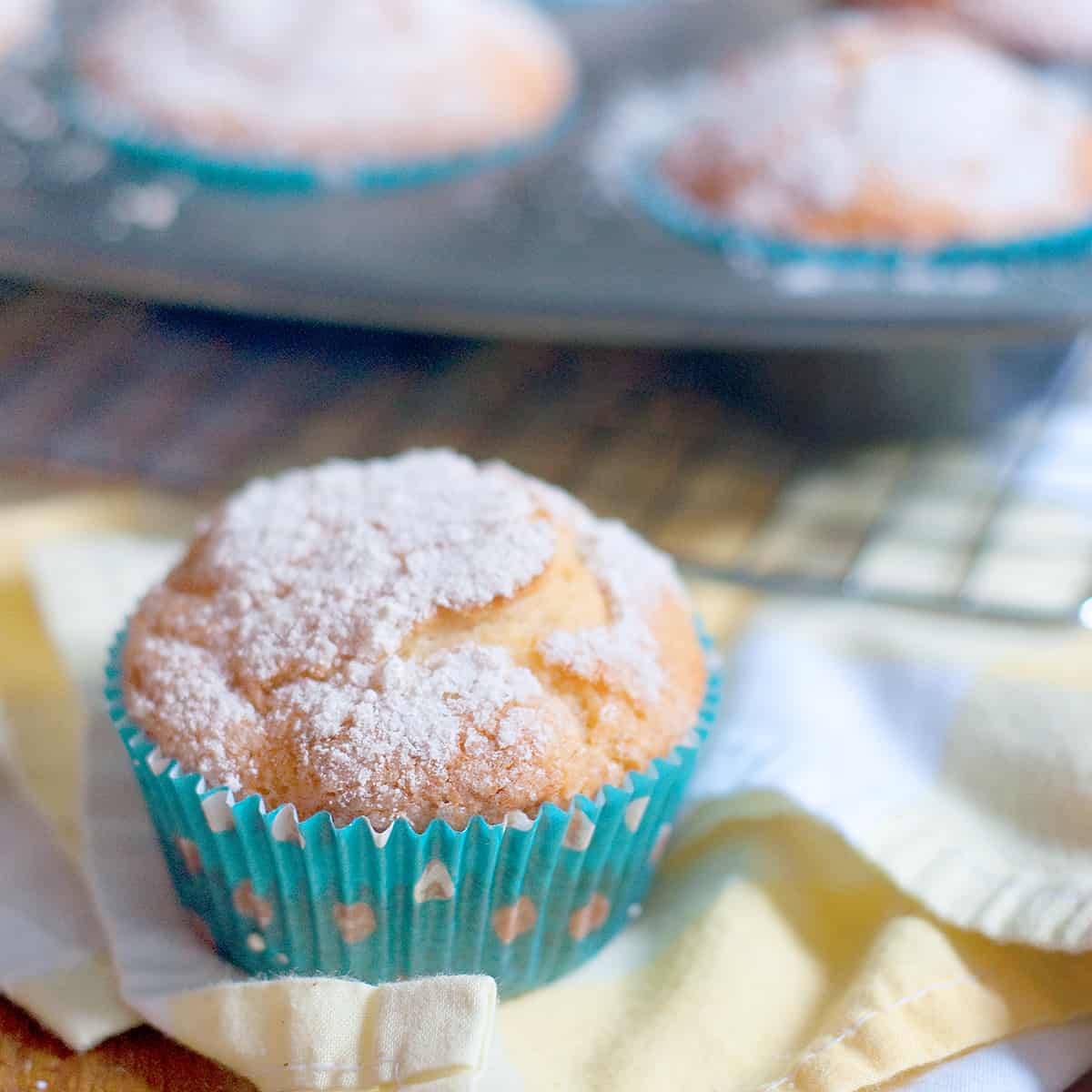 An orange blossom muffin sitting on a yellow and white napkin.