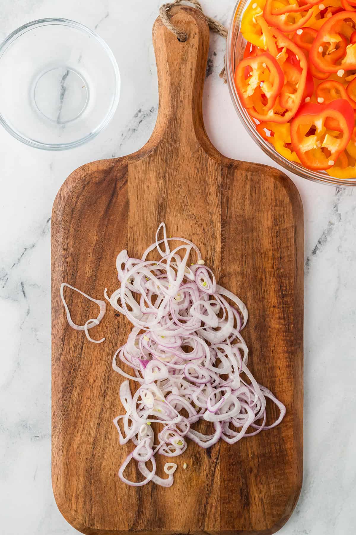 Sliced shallots on a wooden cutting board.