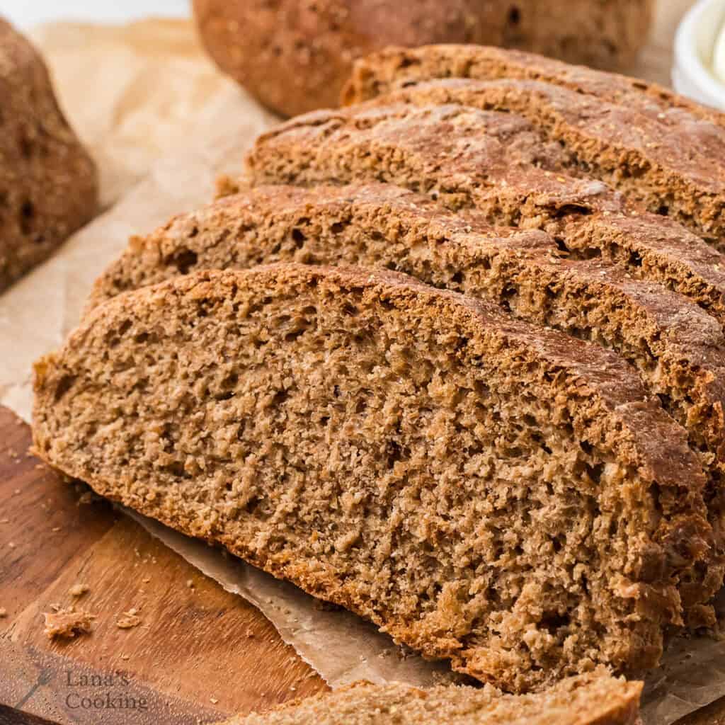 Sliced steakhouse honey wheat bread on a wooden board.