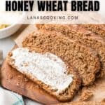Sliced steakhouse honey wheat bread spread with butter on a wooden board.