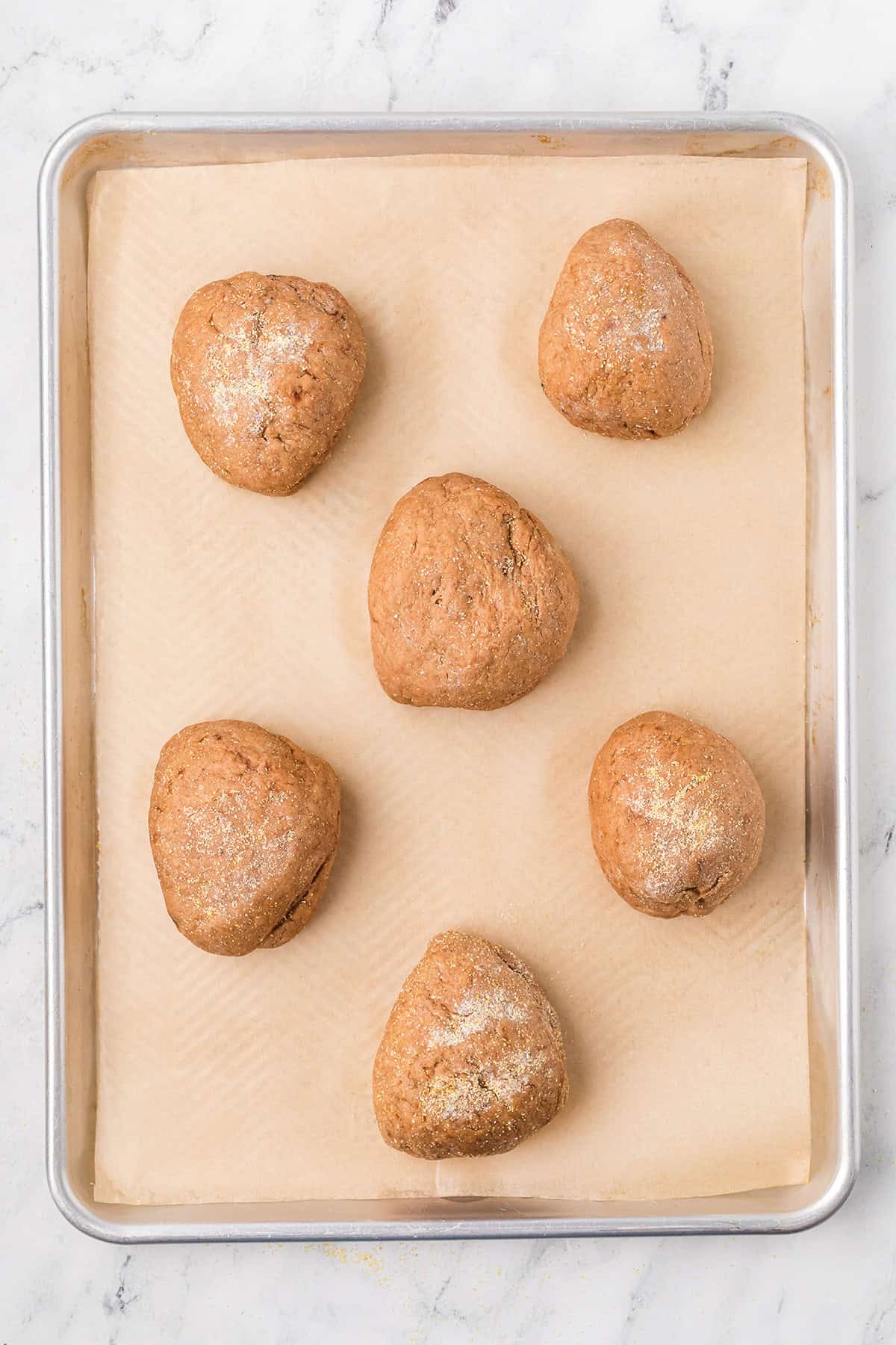 Shaped loaves transferred to a lined baking pan.