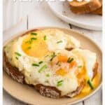 Two slices of toast topped with melted cheese, baked eggs, and chives on a beige plate.