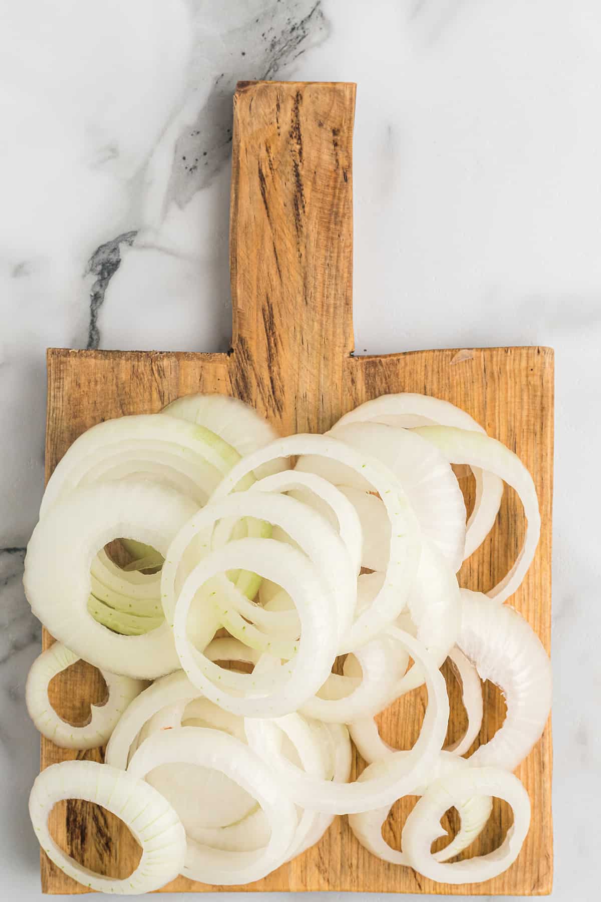 Onion rings on a wooden cutting board.