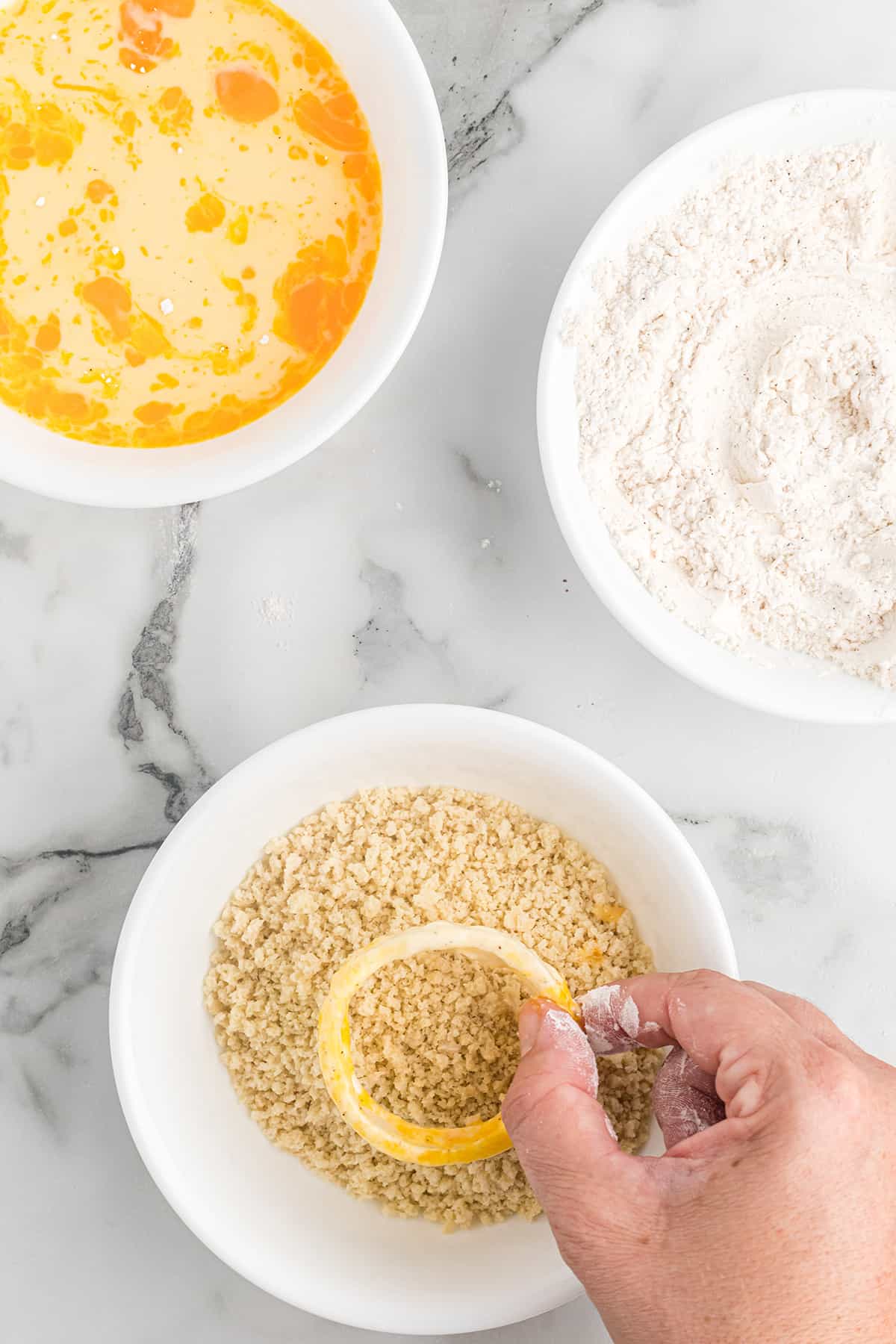 Coating an onion ring with panko breadcrumbs.