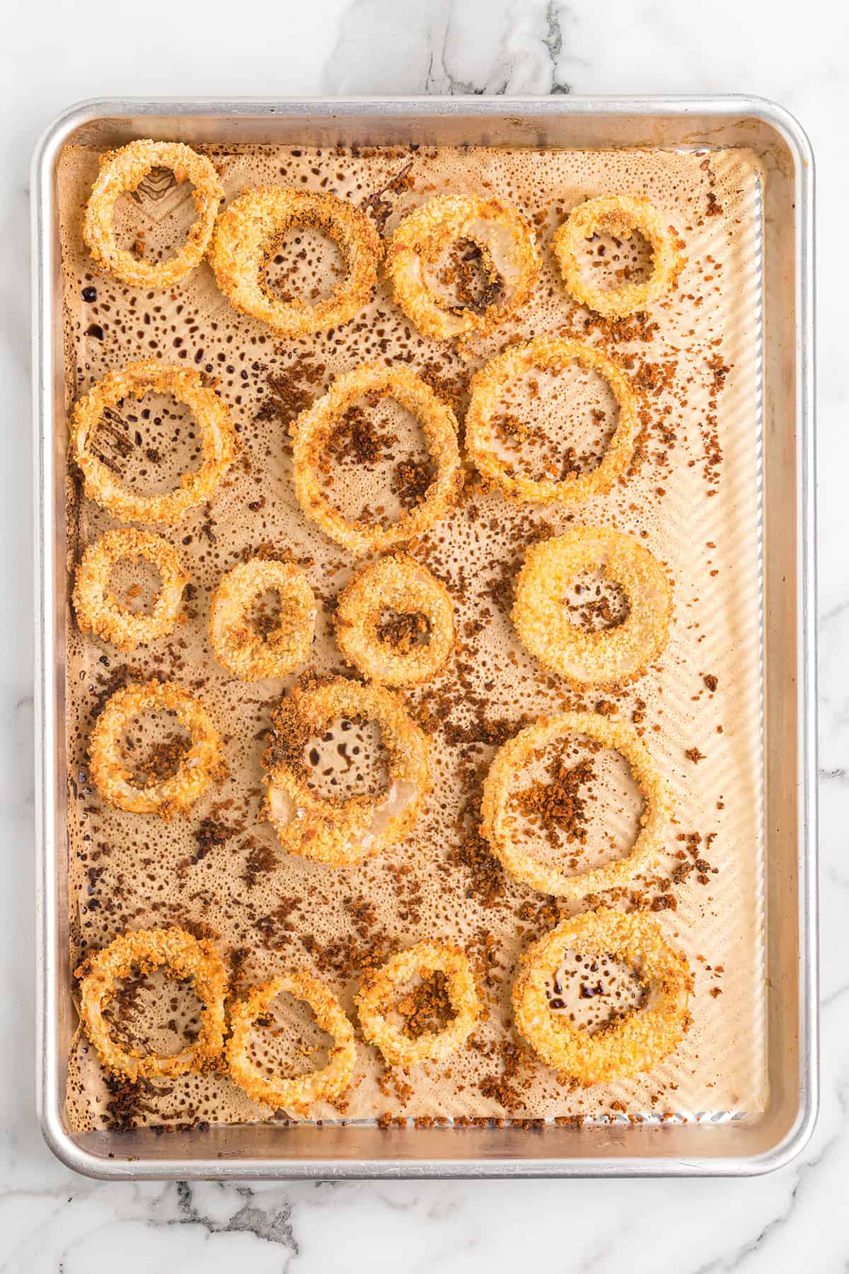 Baked onion rings on a baking pan.