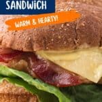 A sandwich with bacon, Swiss cheese, lettuce, and sauce on a whole grain bun. The image includes text describing it as a Chicken, Bacon, and Swiss Sandwich and highlights that it is Warm & Hearty.