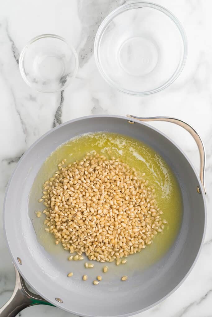 Oil and popcorn kernels added to the flavored butter in the skillet.